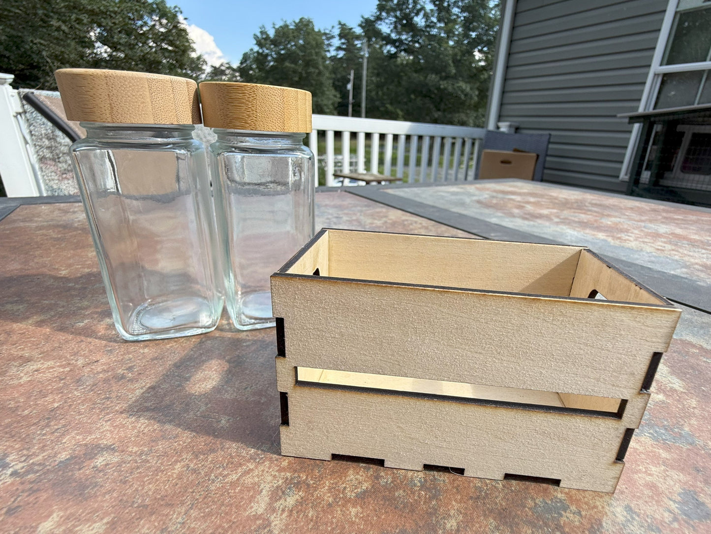 Two glass shaker bottles with bamboo lids in wooden crate