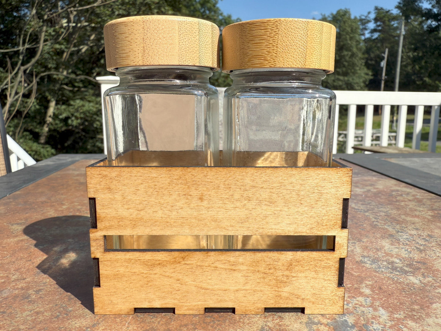 Two glass shaker bottles with bamboo lids in wooden crate