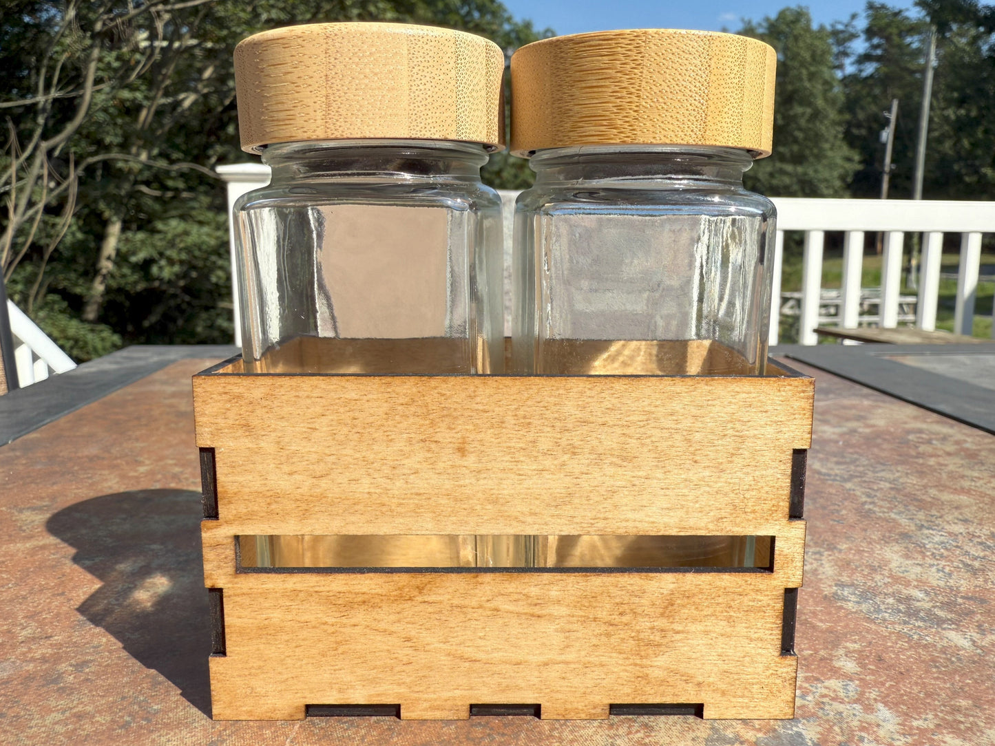Two glass shaker bottles with bamboo lids in wooden crate