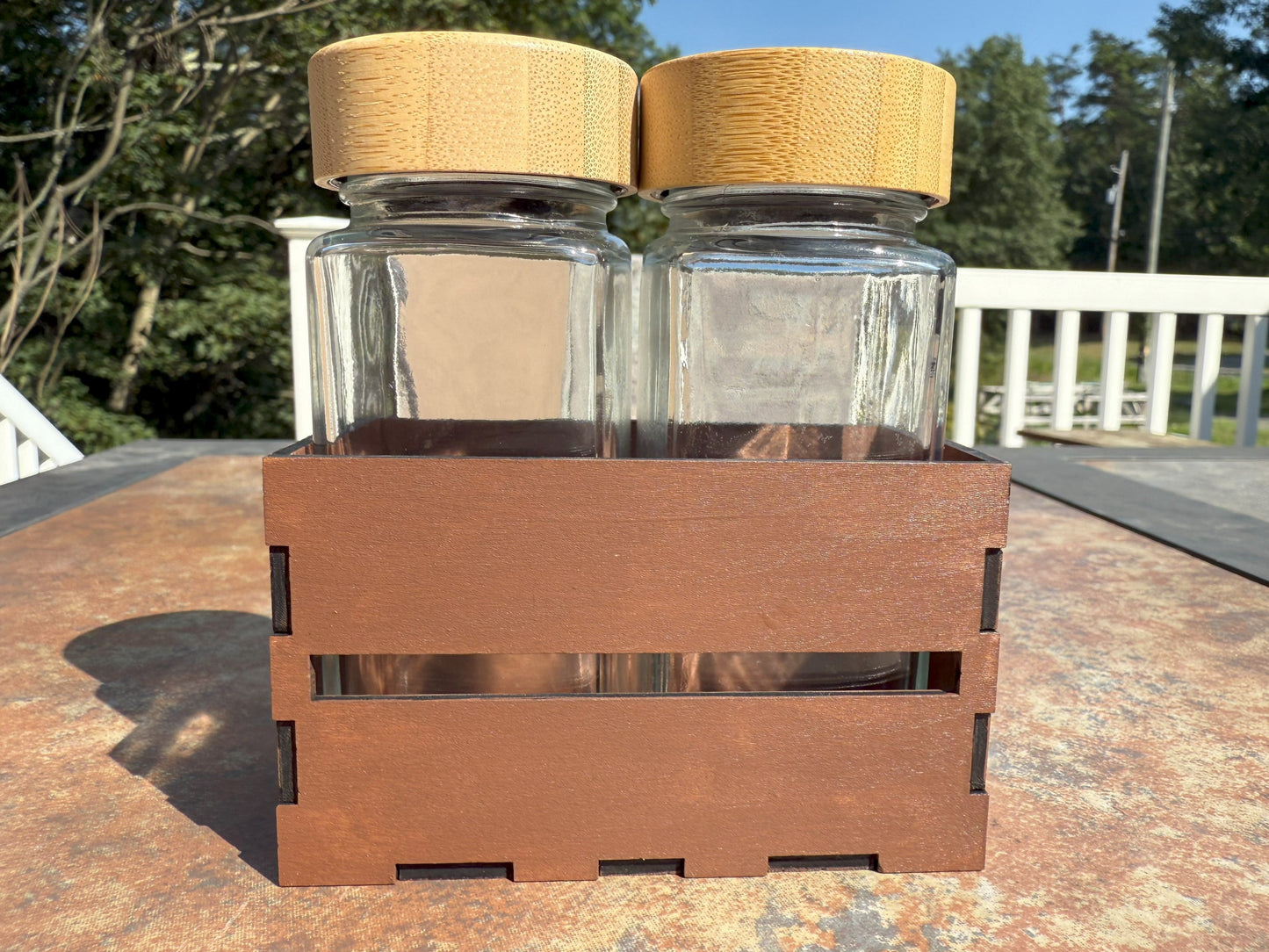 Two glass shaker bottles with bamboo lids in wooden crate