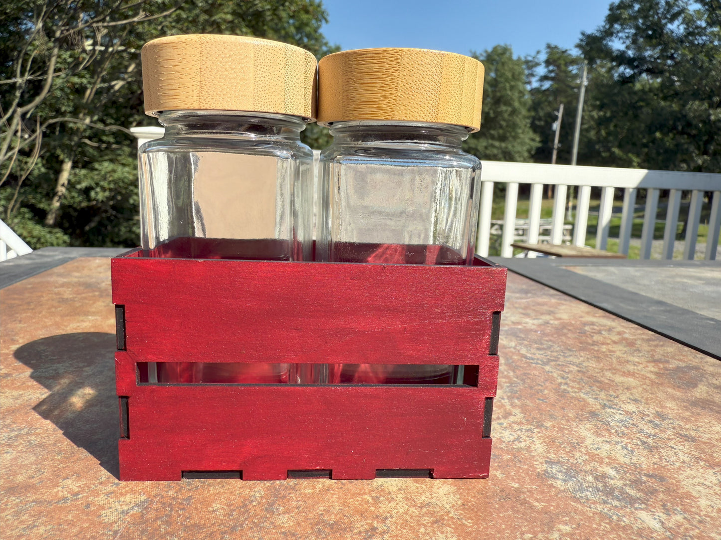 Two glass shaker bottles with bamboo lids in wooden crate