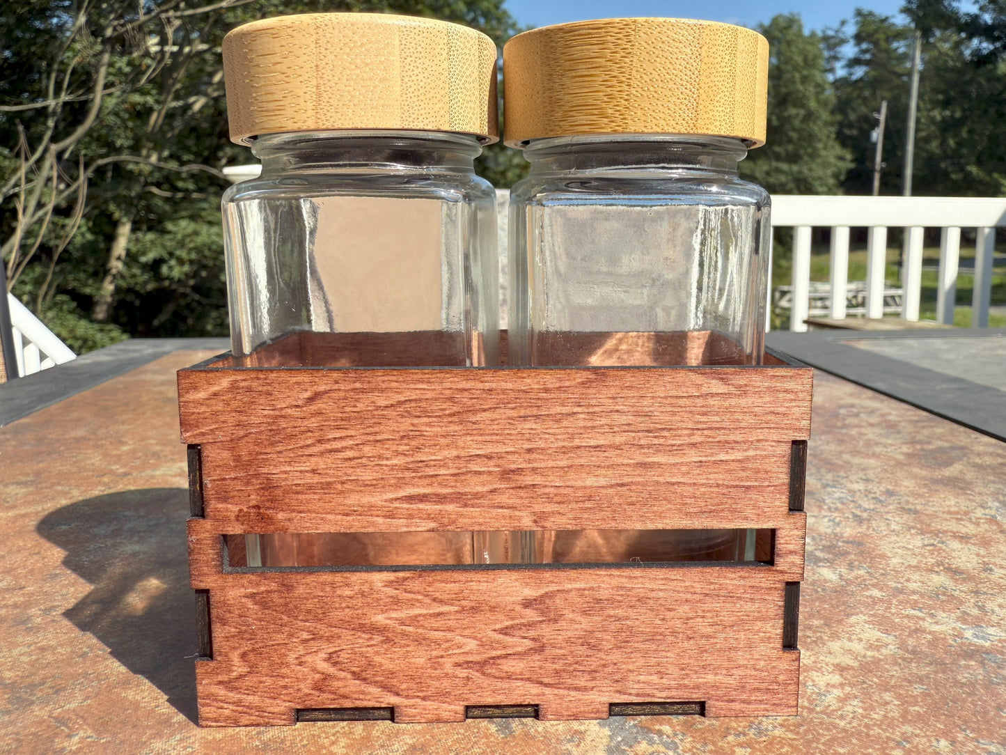 Two glass shaker bottles with bamboo lids in wooden crate