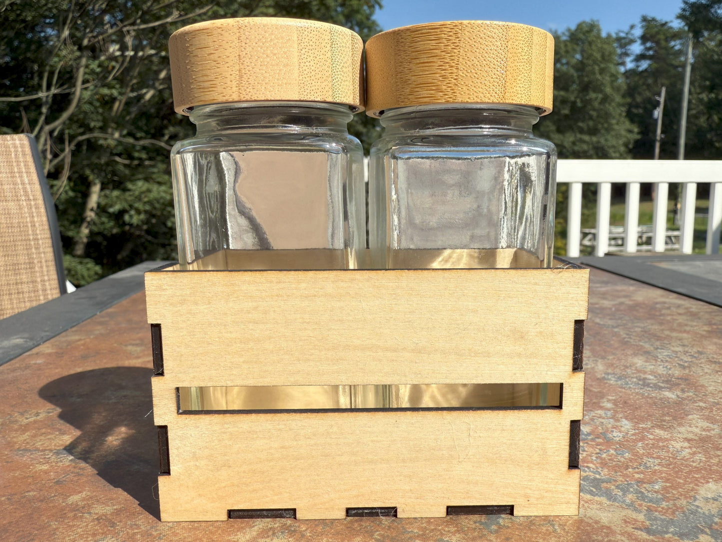 Two glass shaker bottles with bamboo lids in wooden crate