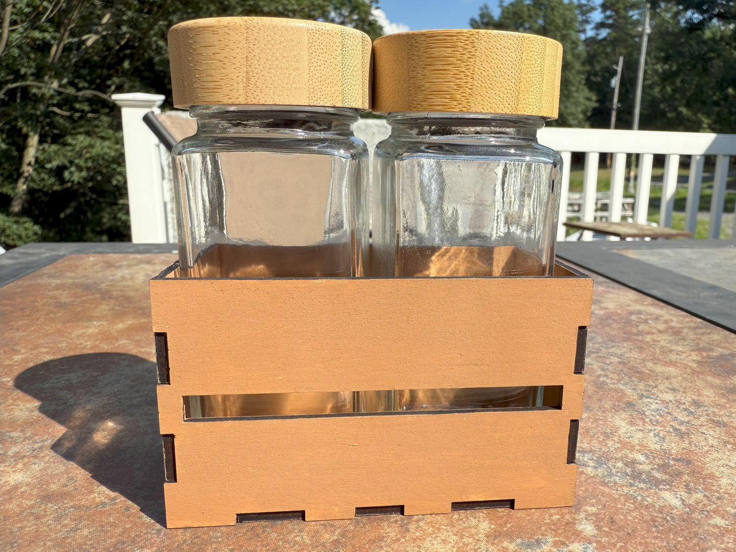 Two glass shaker bottles with bamboo lids in wooden crate