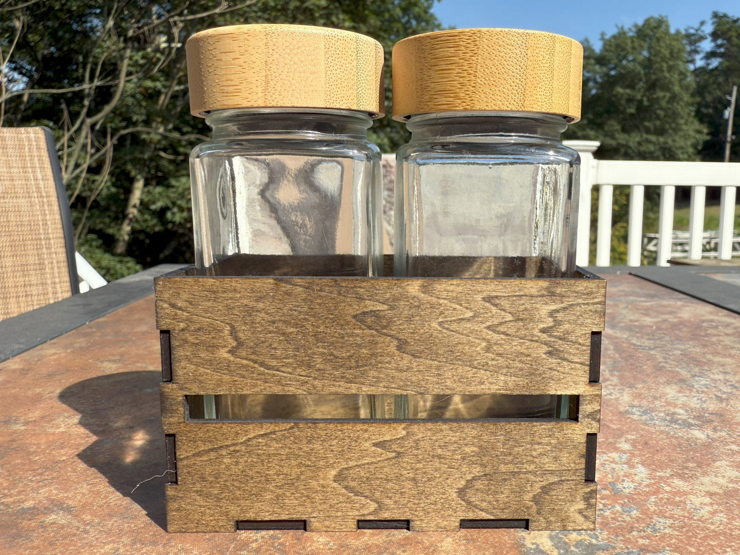 Two glass shaker bottles with bamboo lids in wooden crate