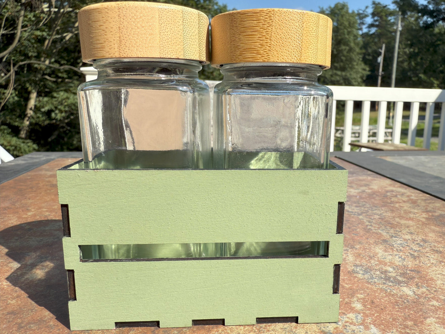 Two glass shaker bottles with bamboo lids in wooden crate