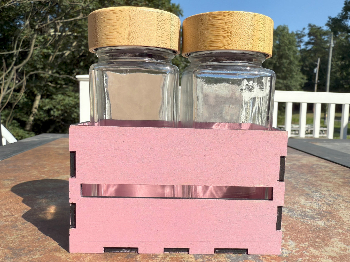 Two glass shaker bottles with bamboo lids in wooden crate