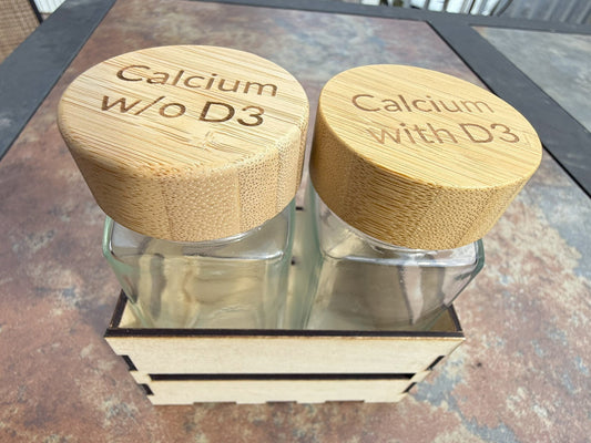 Two glass shaker bottles with bamboo lids in wooden crate