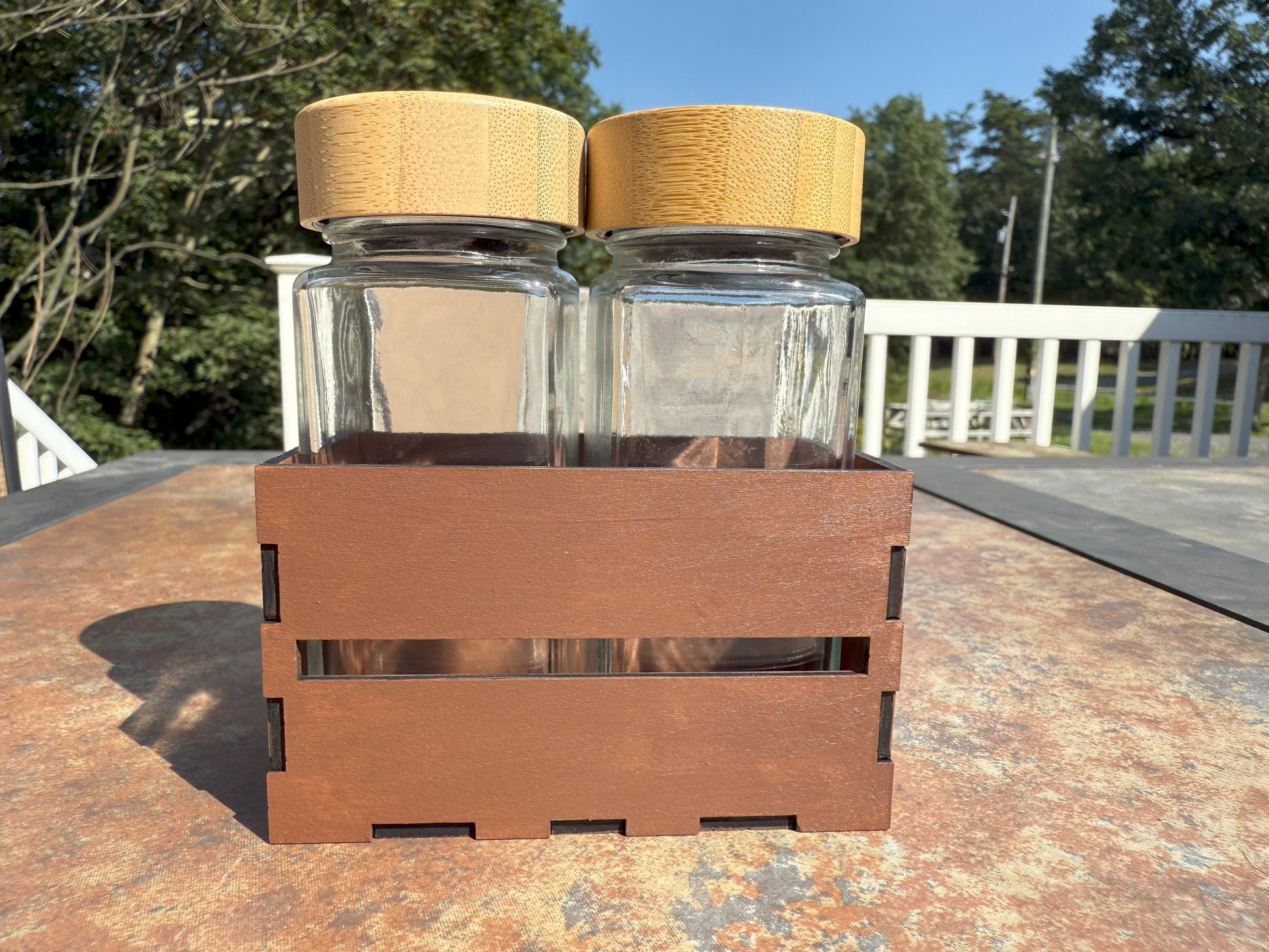 Two glass shaker bottles with bamboo lids in wooden crate